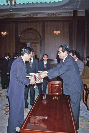 菅首相（左）は１９９５年３月に訪朝し、北朝鮮の金容淳党国際部長からプレゼントを受け取った（山本皓一氏撮影）