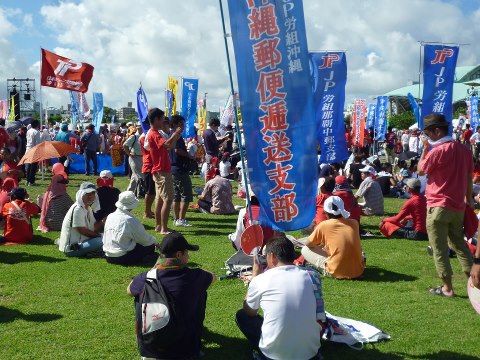 オスプレイ反対県民集会の写真です。座る男性の手元に注目してください。団扇に五星紅旗