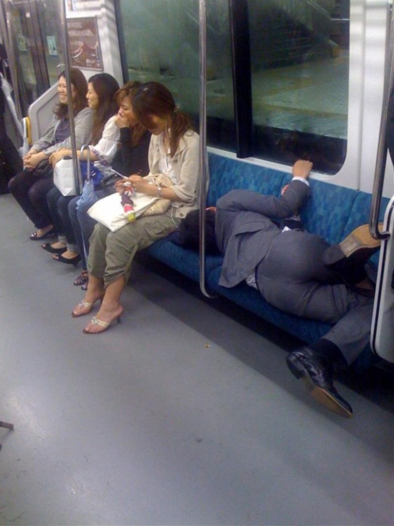 泥酔して電車のシートに寝ころんでるスーツの男