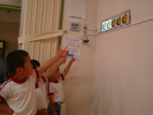 おひさまが発電していることがひと目でわかるパネルを指さす園児たち（飯田市・明星保育園）