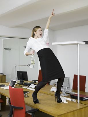 young business woman celebrating on desk in office
