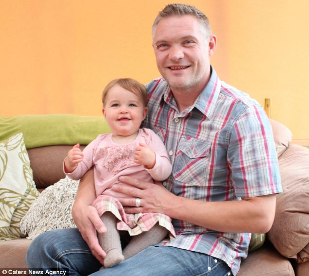 Home and healthy: Mr Page, 39, clutches his first-born, who is now as healthy as any 15-month-old baby