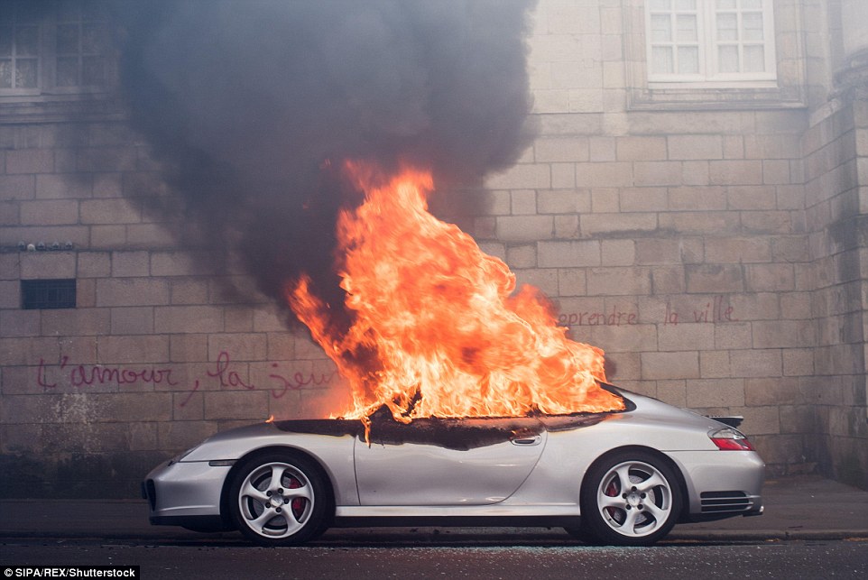 Engulfed in flames: A Porsche is set alight in Nantes in western France by angry protesters demonstrating against a contested labour bill