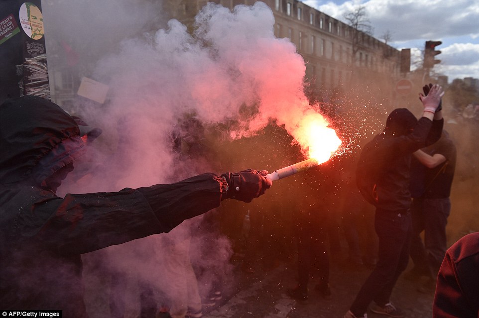 A protester holds a lit flare during a demonstration in Paris today. Young people have been at the forefront of the protest movement