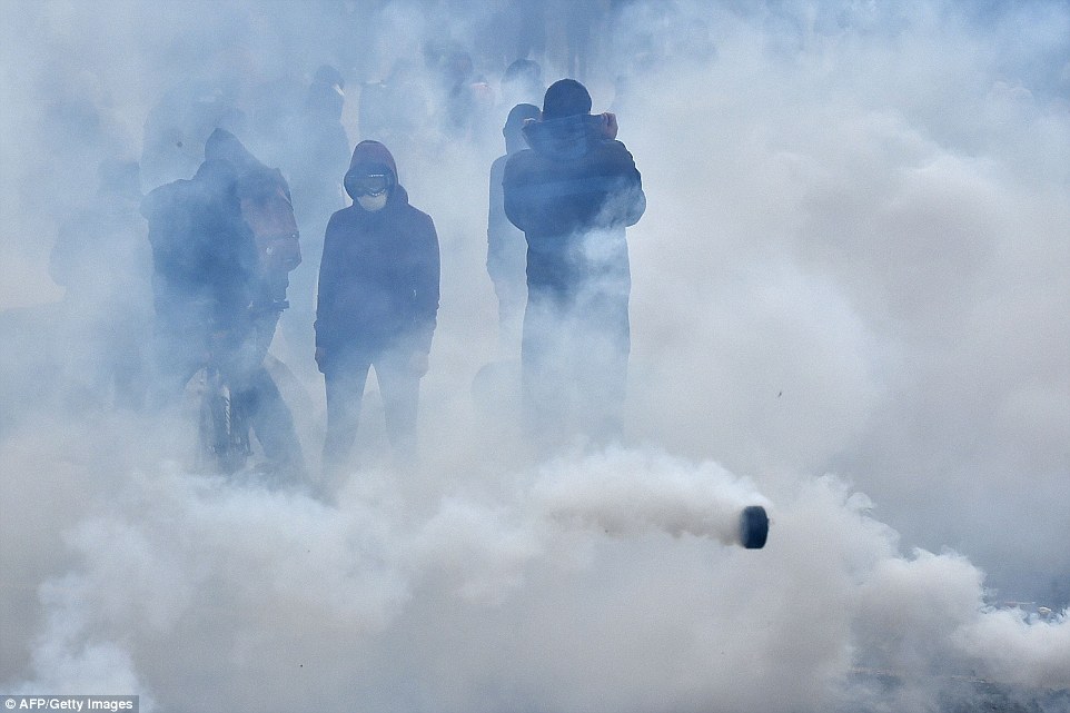Protesters are pictured through tear gas as they protest against the the reform, billed as an effort to reduce chronic unemployment