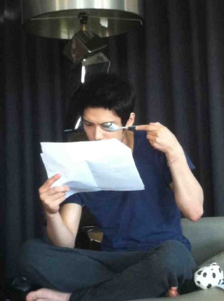 ものもらい（麦粒腫）ができた方の目をスプーンで隠して台本を読んでいるＪＹＪのキム・ジェジュン（写真＝本人のツイッター）。