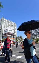 晴天の下、日傘を差して交差点を渡る歩行者=14日午後3時すぎ、那覇市久茂地(田嶋正雄撮影)