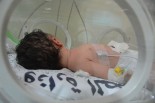 保育器の中で呼吸を続ける女の子は、母親が爆撃で殺されたことを知る由もない。＝26日、デルバラ病院　写真：筆者＝