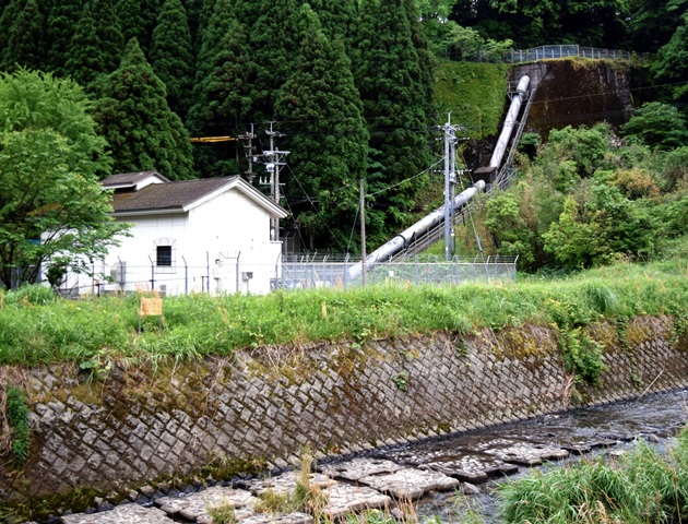写真：小山田発電所と、水が流れてくる鉄管。手前は甲突川＝鹿児島市小山田町
