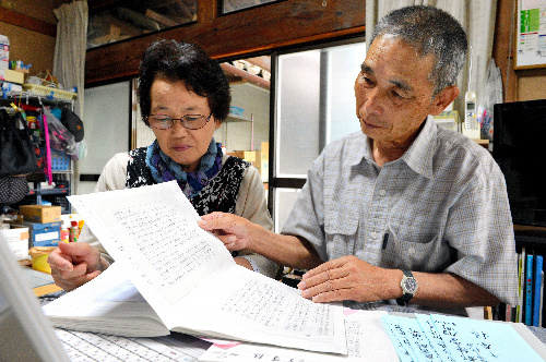 写真：「神山友愛の里通信」の読者からの手紙をまとめたノートを見る大友章生さんと妻の祥子さん。「今でも避難生活でつらい思いをしている方々からの手紙を読むと胸が詰まります」と大友さんは話した＝福島県南相馬市鹿島区北屋形、小川智撮影