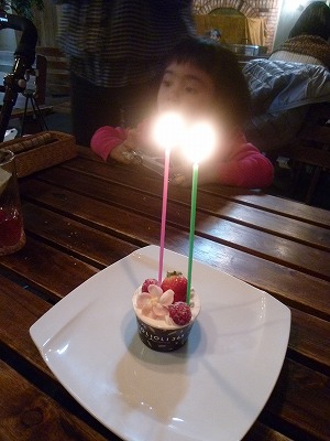 誕生日ケーキに、ろうそく２本（向こう側にいるのは娘）