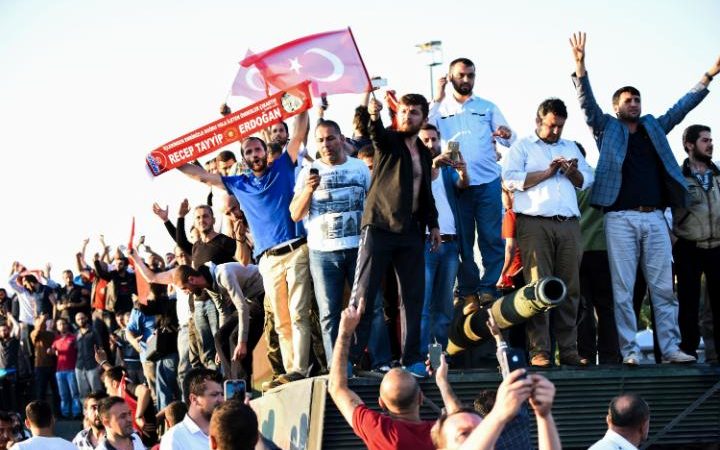 People stand and celebrate on an army tank after taking over a military position on the Bosphorus bridge in Istanbul on July 16