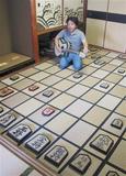 将棋の面白畳を敷いた和室で畳のギターを抱える西脇一博さん＝京都市上京区